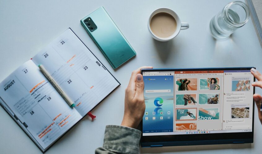 person using Windows 11 computer beside white ceramic mug on white table